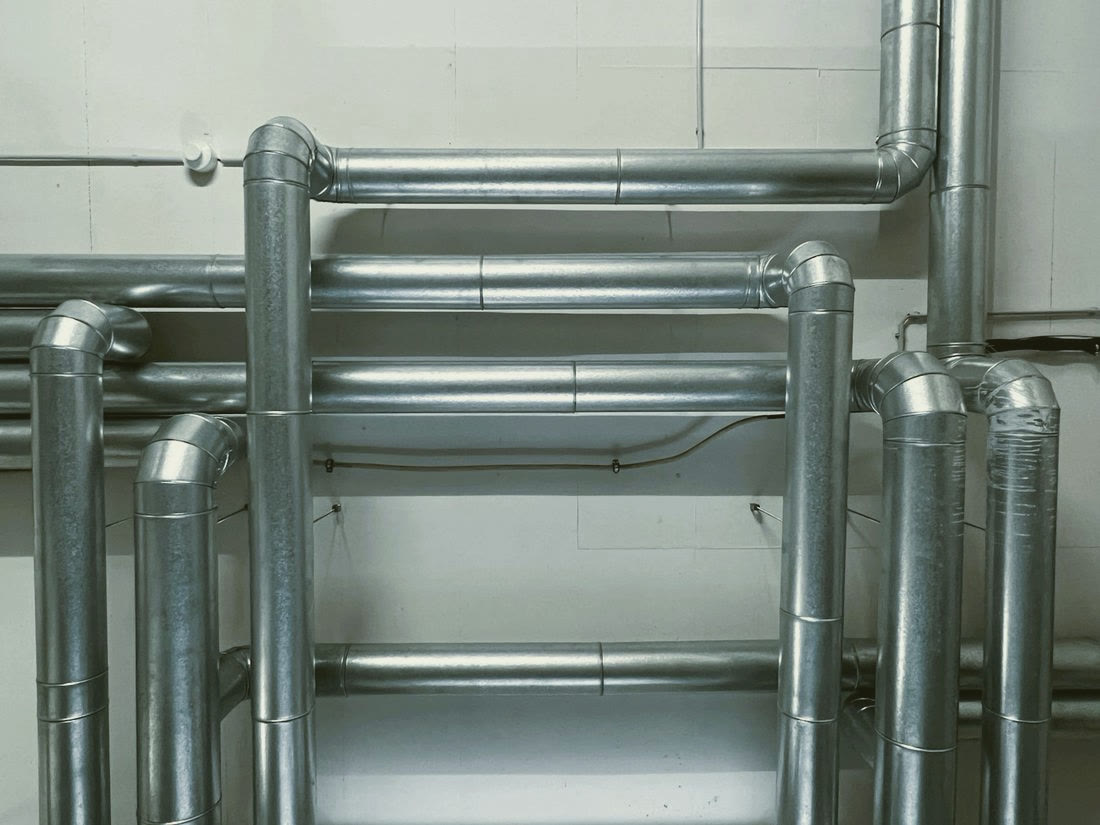 Galvanised ductwork running along a plant room wall