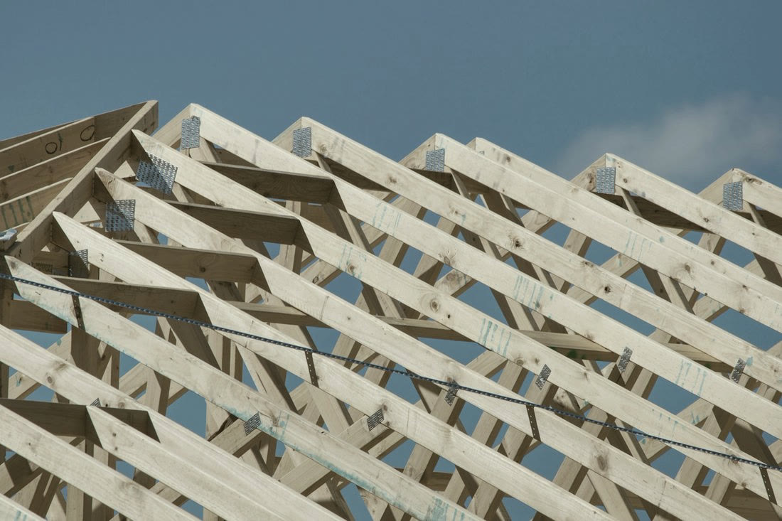 Timber roof trusses against a clear blue sky